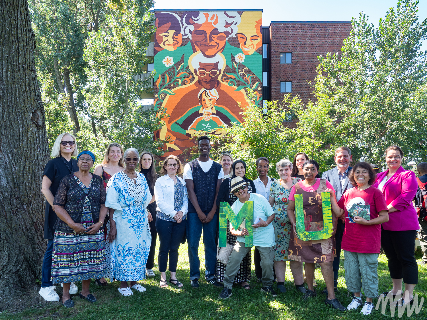 Lors du lancement de la nouvelle murale de MU, l'artiste Franco Égalité entouré des résidants et des partenaires du projet.