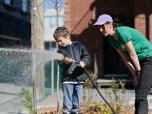 L'horticultrice de Vert le Nord apprend aux enfants à arroser correctement les arbustes fraîchement plantés.